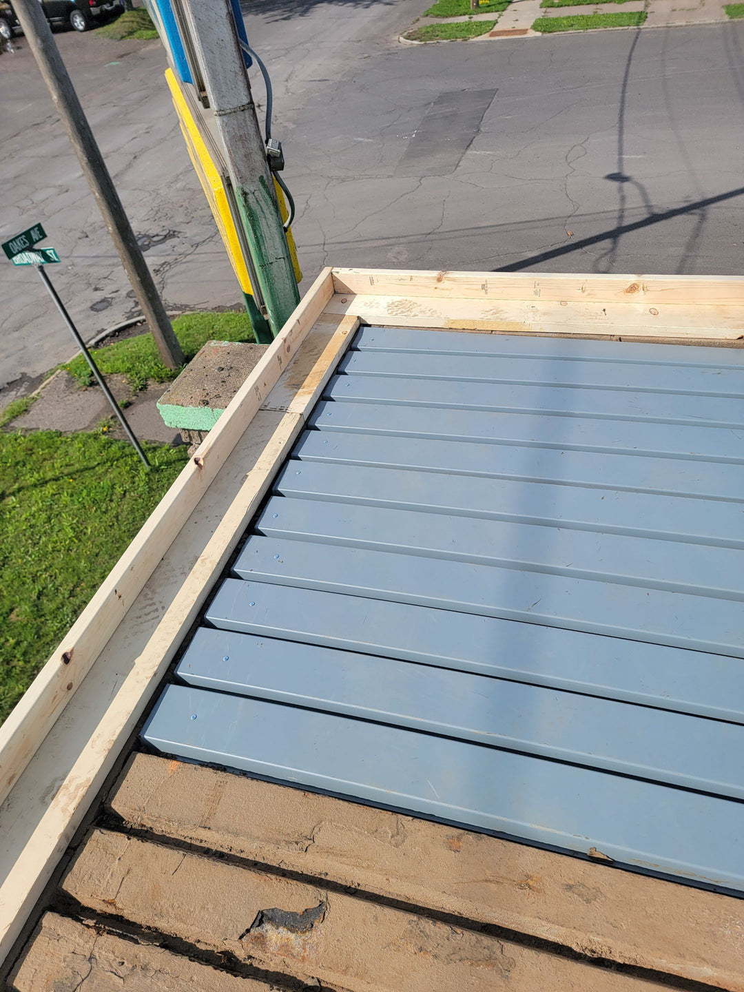 Metal roof panels on a construction site with a street in the background