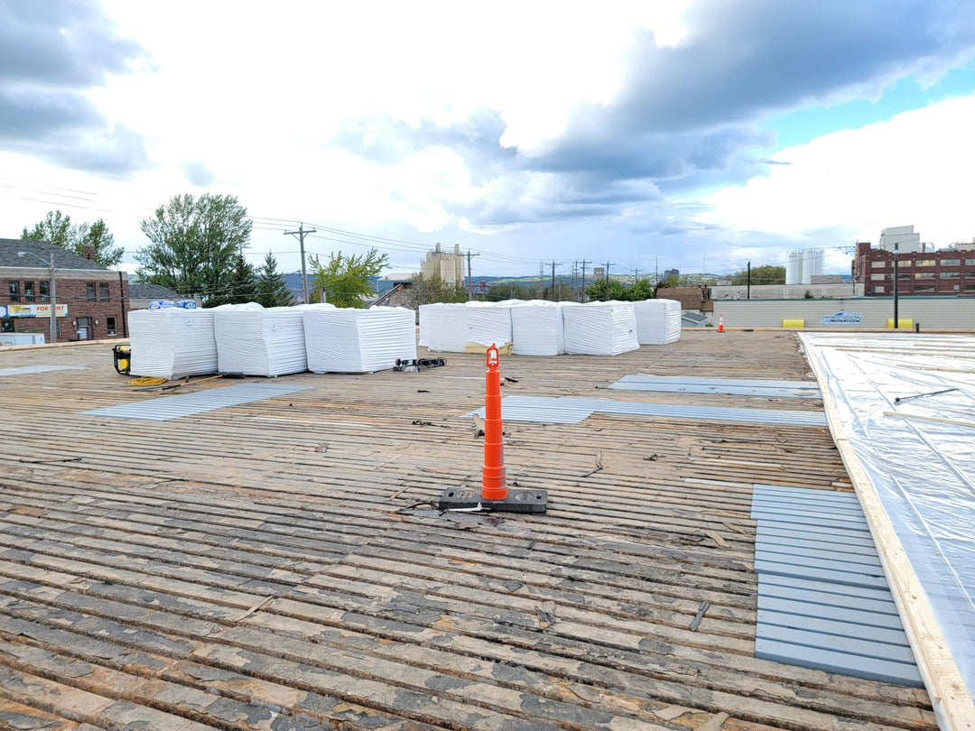 Flat roof deck exposed during full replacement — new insulation boards staged for installation.
