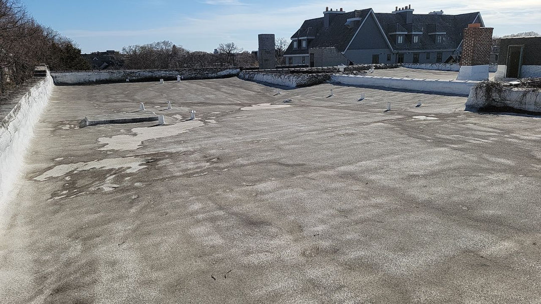 Aged commercial flat roof with surface erosion and staining