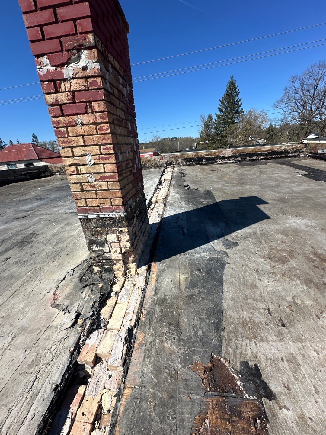 Damaged roof with exposed insulation and a brick chimney
