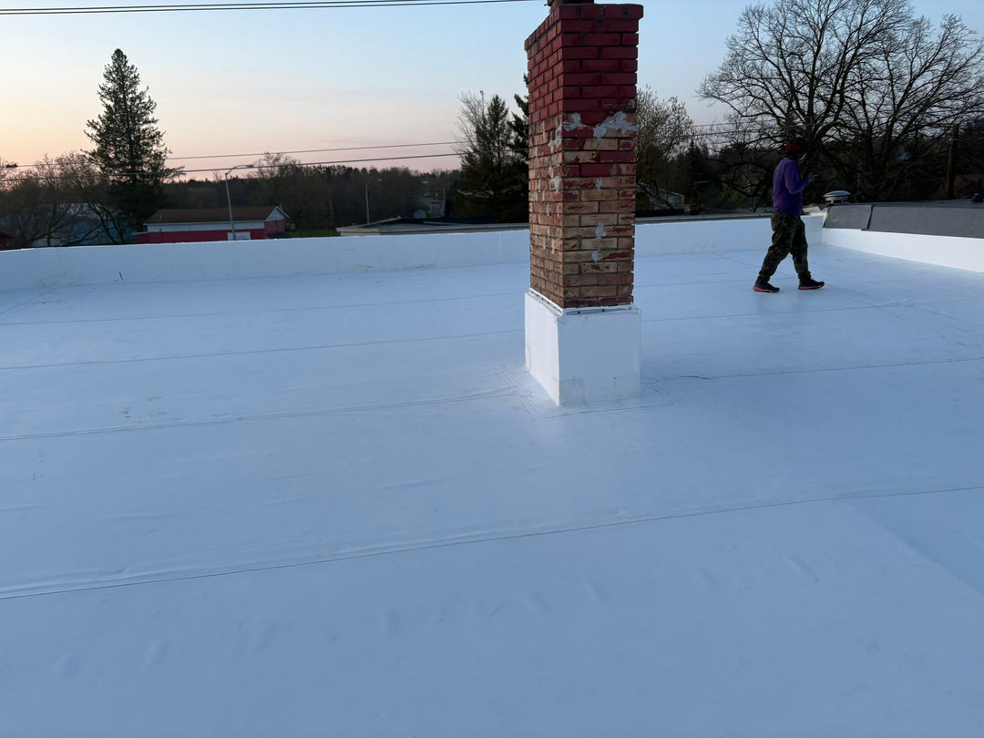 Completed white roof installation with new chimney flashing.