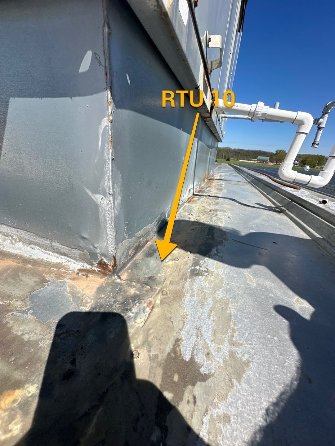 Annotated roof inspection showing failed flashing at RTU 10 rooftop unit with rust staining