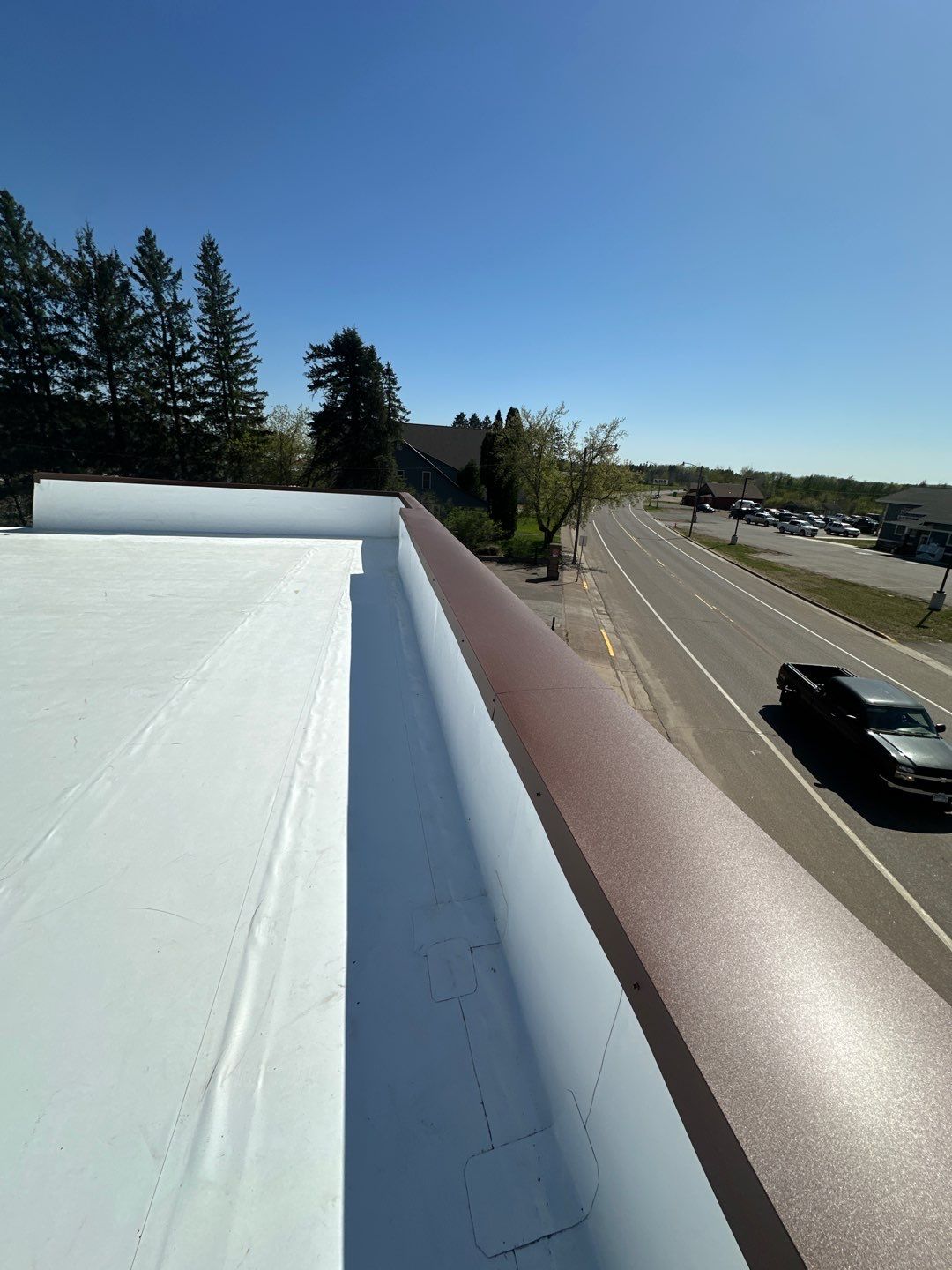Completed white TPO flat roof with clean drip edge and parapet detail