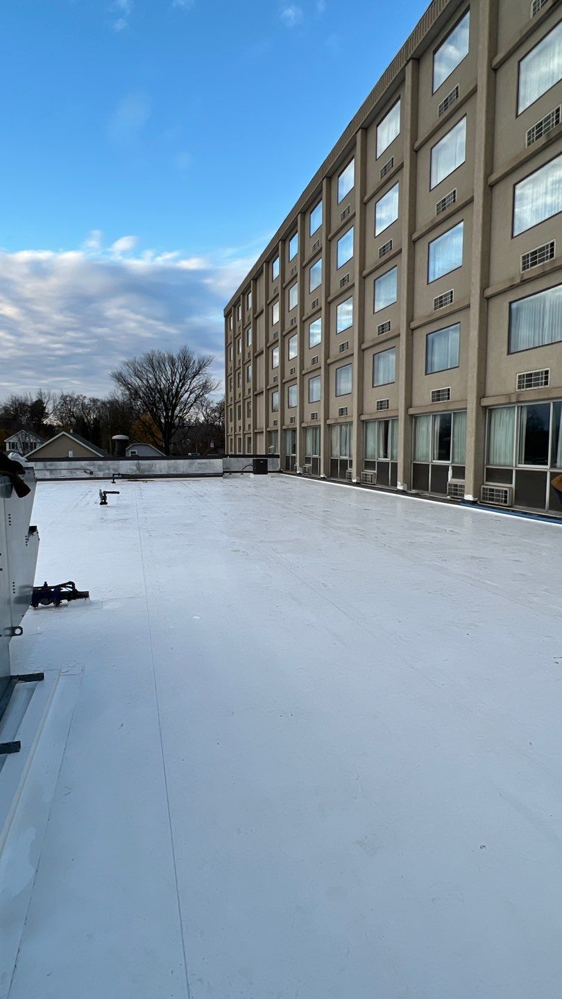 Completed white TPO flat roof on multi-story commercial building — large-scale roofing installation
