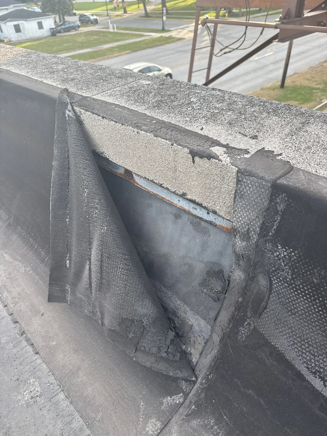 Close-up of a roof with damaged shingles and a protective covering.