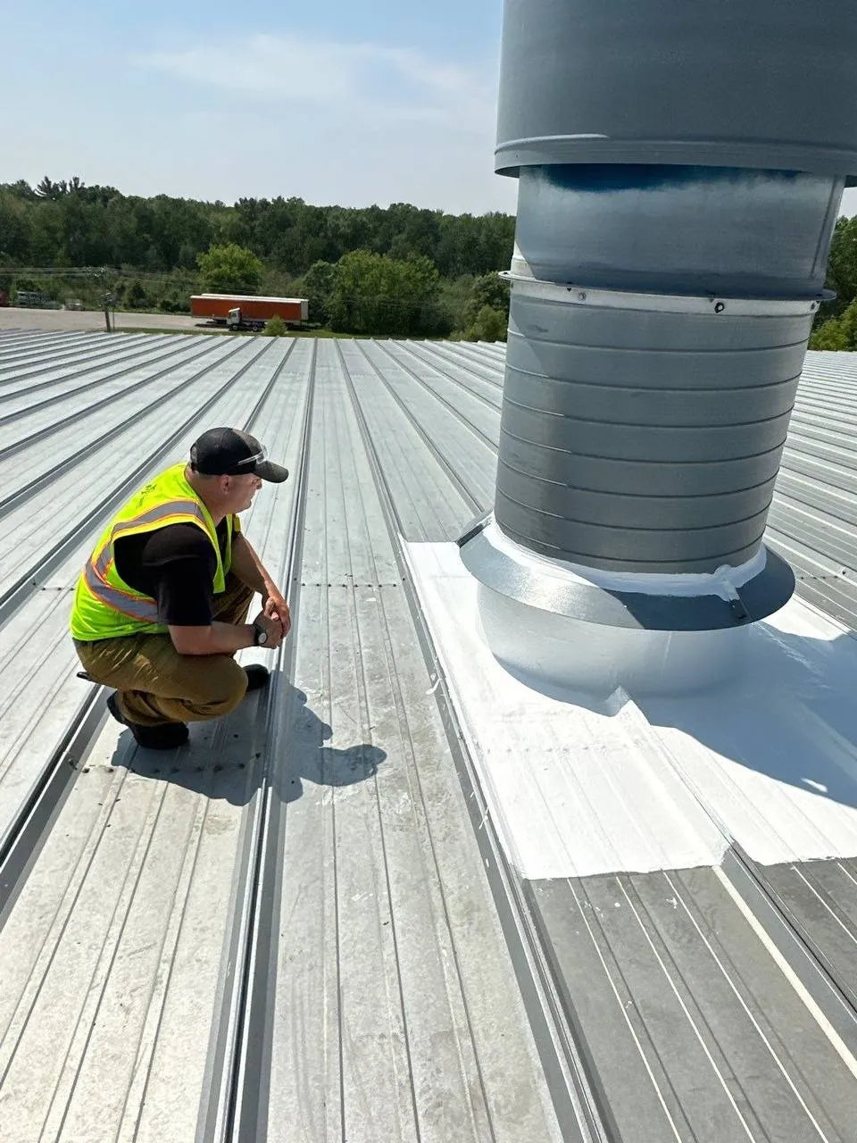 Pristine Industrial Roofing technician inspecting liquid coating detail around industrial exhaust fan on commercial metal roof